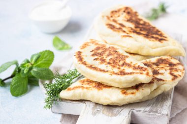 Frying pan baked flat bread with fresh herbs and yogurt dressing. Khychiny or qutab - traditional caucasian or Azerbaijani flatbread. clipart