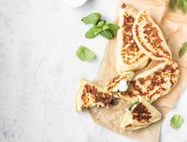 Taze ot ve yoğurt sos ile düz ekmek kızartma tavası pişmiş. Khychiny veya qutab - geleneksel beyaz veya Azeri gözleme.
