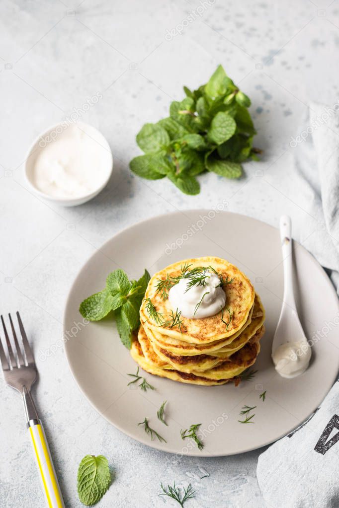 Zucchini fritters served with fresh herbs and yogurt dressing. Vegetarian zucchini pancakes. Copy space.