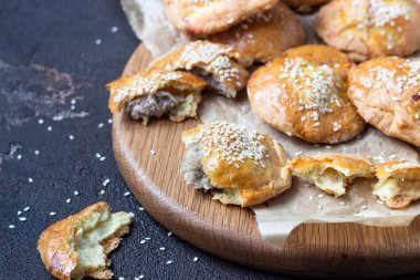 Taze et mini pies eski koyu kahverengi zemin, rustik tarzı bir kağıt üzerinde. Taze pişmiş pasties et (tavuk veya hindi) ile dolu. Kopya alanı.