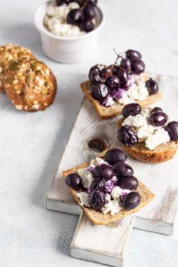 Bruschetta ricotta veya krem peynir ve hafif ahşap kesme tahtası üzerinde pişmiş üzüm ile.