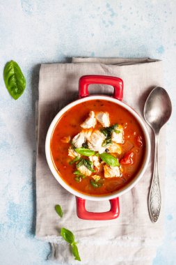 Tavuk, sebze ve fesleğen ile sıcak domates çorbası. Hafif beton arka plan. Uzay kopyalayın. Üstten görünüm. 