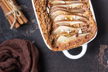 Fındık ve bal bir tavada pişirme için Diyet kek yulaf ezmesi, tarçın ve armut ile süslenmiş. Koyu kahverengi taş beton. Üstten görünüm, kopya alanı.