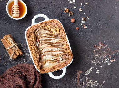 Fındık ve bal bir tavada pişirme için Diyet kek yulaf ezmesi, tarçın ve armut ile süslenmiş. Koyu kahverengi taş beton. Üstten görünüm, kopya alanı.