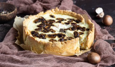 Quiche petrol ve koyu kahverengi beton zemin üzerine peynir ile. Mantar ile tuzlu tart. Uzay baş.