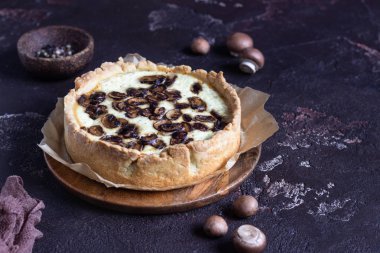 Quiche petrol ve koyu kahverengi beton zemin üzerine peynir ile. Mantar ile tuzlu tart. Uzay baş.