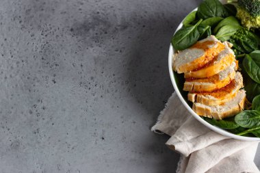 Ispanak, brokoli ve beyaz tabakta narenciye sosu ile tavuk göğsü. Gri beton arka plan. Uzay kopyalayın. Sağlıklı Diyet öğle veya akşam yemeği. Keto diyet.