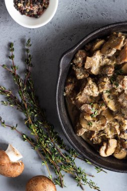 Mantar ve kekik bir dökme demir tavada et ihtiva eder. Gri beton arka plan. Kopya alanı. 