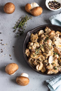 Mantar ve kekik bir dökme demir tavada et ihtiva eder. Gri beton arka plan. Kopya alanı. 