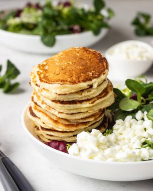 Peynirli tuzlu kek yeşil salata karışımı ve taze çiftlik süzme peynir ile görev yaptı. Sağlıklı kahvaltı ve öğle yemeği. Hafif beton arka plan. Kopya alanı.