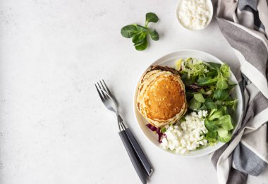 Peynirli tuzlu kek yeşil salata karışımı ve taze çiftlik süzme peynir ile görev yaptı. Sağlıklı kahvaltı ve öğle yemeği. Hafif beton arka plan. Kopya alanı.