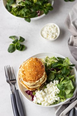 Peynirli tuzlu kek yeşil salata karışımı ve taze çiftlik süzme peynir ile görev yaptı. Sağlıklı kahvaltı ve öğle yemeği. Hafif beton arka plan. Kopya alanı.