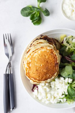 Peynirli tuzlu kek yeşil salata karışımı ve taze çiftlik süzme peynir ile görev yaptı. Sağlıklı kahvaltı ve öğle yemeği. Hafif beton arka plan. Kopya alanı.