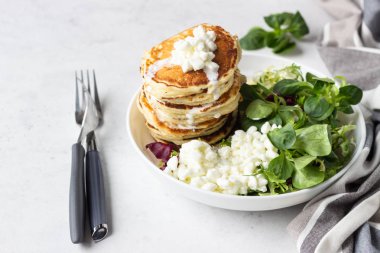 Peynirli tuzlu kek yeşil salata karışımı ve taze çiftlik süzme peynir ile görev yaptı. Sağlıklı kahvaltı ve öğle yemeği. Hafif beton arka plan. Kopya alanı.