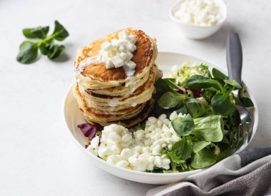 Peynirli tuzlu kek yeşil salata karışımı ve taze çiftlik süzme peynir ile görev yaptı. Sağlıklı kahvaltı ve öğle yemeği. Hafif beton arka plan. Kopya alanı.