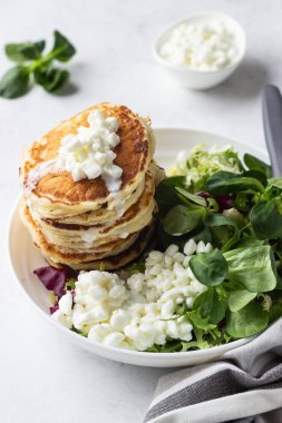Peynirli tuzlu kek yeşil salata karışımı ve taze çiftlik süzme peynir ile görev yaptı. Sağlıklı kahvaltı ve öğle yemeği. Hafif beton arka plan. Kopya alanı.