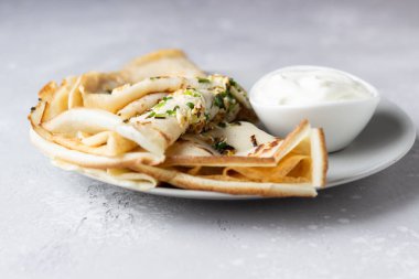 İnce krep veya yumurta, yeşil soğan ve doğal yoğurt veya ekşi krema ile krep. Kahvaltı veya brunch. Hafif beton arka plan. Kopya alanı.