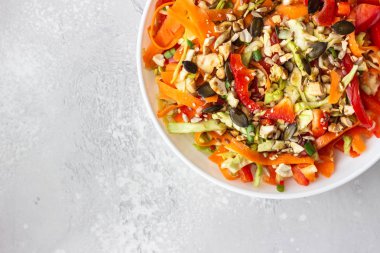 Beyaz lahana, havuç, biber, susam ve kaju fıstığı ile Asya lahana salatası. Sağlıklı gıda kavramı. Hafif beton arka plan. Kopya alanı.