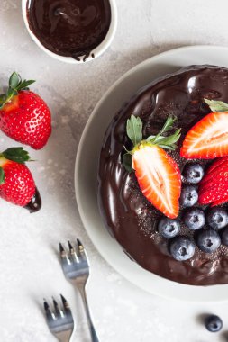 Peynirli kuru üzüm ile dekore edilmiş çikolata sır ve taze çilek ve yaban mersini.