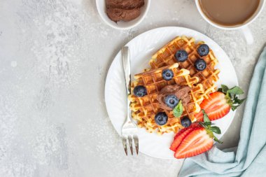 Çikolata sosu, çilek ve nane hafif gri arka plan üzerinde Belçika waffle ile plaka. Kahvaltı ve öğle yemeği. Kopya alanı.