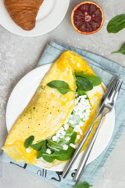 Omelette with spinach, avocado and fresh farm cottage cheese (tvorog) with red orange juice on a light grey background. Healthy breakfast or diet lunch. Copy space.