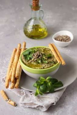 Mung fasulye, nane ve tohumları ile daldırma Grissini veya tuzlu ekmek çubukları ile hizmet vermektedir. Yeşil humus. Açık gri arka plan. Boşluk Kopyala. Sağlıklı snack.