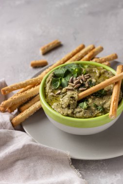 Mung fasulye, nane ve tohumları ile daldırma Grissini veya tuzlu ekmek çubukları ile hizmet vermektedir. Yeşil humus. Açık gri arka plan. Boşluk Kopyala. Sağlıklı snack.