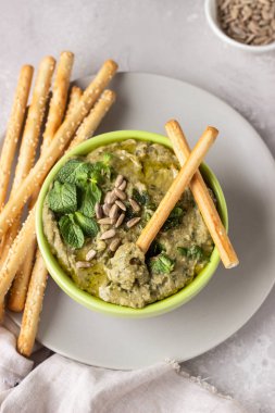 Mung fasulye, nane ve tohumları ile daldırma Grissini veya tuzlu ekmek çubukları ile hizmet vermektedir. Yeşil humus. Açık gri arka plan. Boşluk Kopyala. Sağlıklı snack.