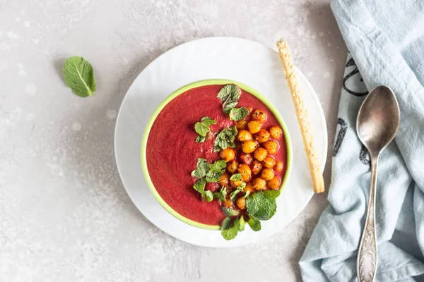 Spring detox beetroot soup with mint, coconut milk and baked chickpeas on a light grey concrete background, copy space. Dieting, clean eating, weight loss, vegetarian food concept.