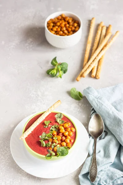 Spring detox beetroot soup with mint, coconut milk and baked chickpeas on a light grey concrete background, copy space. Dieting, clean eating, weight loss, vegetarian food concept.