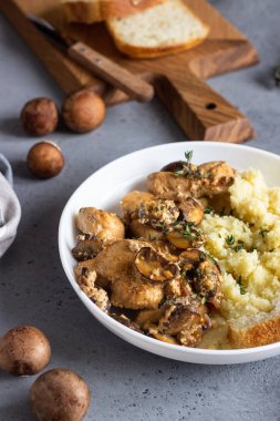 Mantar ile krem sos tavuk göğsü, soğan ve kekli beyaz bir plaka kuskus ile hizmet.