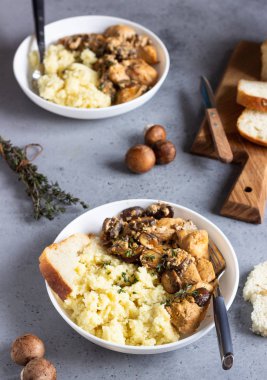 Mantar ile krem sos tavuk göğsü, soğan ve kekli beyaz bir plaka kuskus ile hizmet.