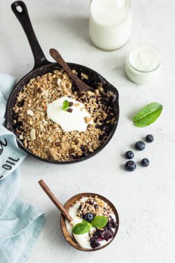 Yulaf ezmesi taze yaban mersini ve doğal yoğurt ile dökme demir tavada ufalamak. Sağlıklı gıda kavramı. 
