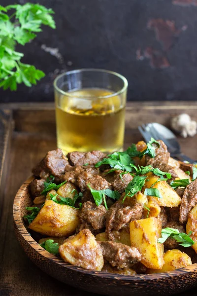 Meat stew with potatoes and parsley in wooden dish. Traditional Portuguese meat stew. Wooden background.