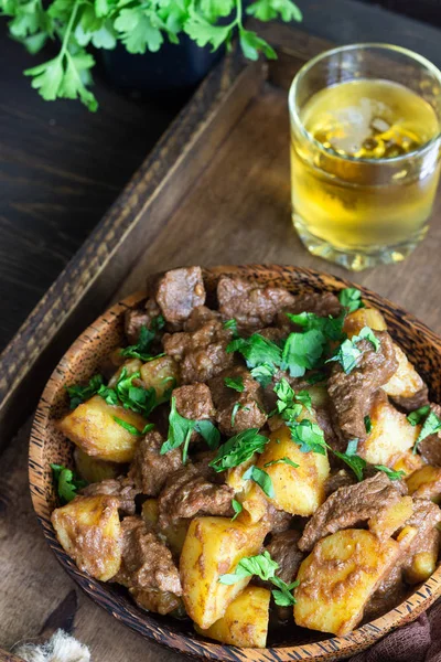 Meat stew with potatoes and parsley in wooden dish. Traditional Portuguese meat stew. Wooden background.