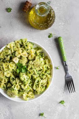 Beyaz bir tabak ta yeşil soslu makarna ve kavurma karnabahar. Kopyalama alanı.