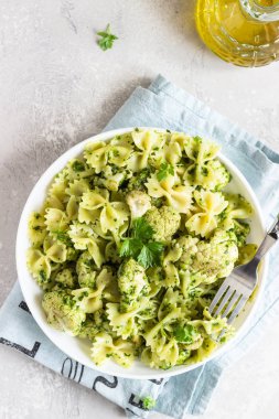 Beyaz bir tabak ta yeşil soslu makarna ve kavurma karnabahar. Kopyalama alanı.