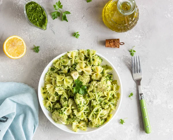 Beyaz bir tabak ta yeşil soslu makarna ve kavurma karnabahar. Kopyalama alanı.