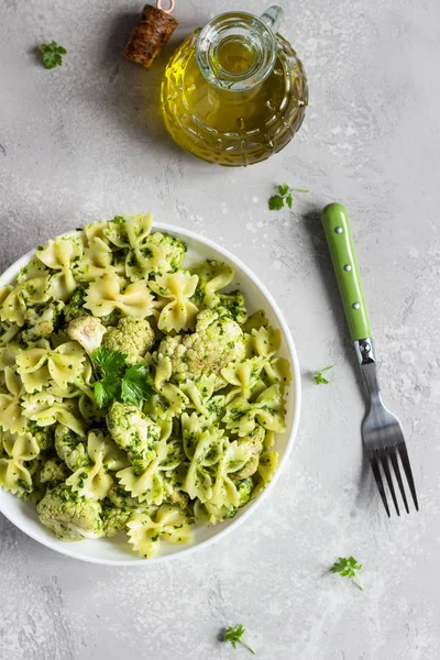 Beyaz bir tabak ta yeşil soslu makarna ve kavurma karnabahar. Kopyalama alanı.