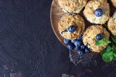 Taze çilek ve nane yaprakları ile blueberry kekler koyu kahverengi taş arka plan üzerinde. Kopyalama alanı.