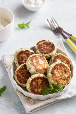 Yeşil bezelye, dereotu, nane ve sos ile süzme peynir börek (syrniki). Hafif taş arka plan. Sağlıklı kahvaltı veya diyet öğle yemeği. Boşluk Kopyala.