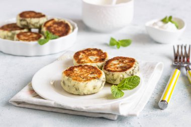 Yeşil bezelye, dereotu, nane ve sos ile süzme peynir börek (syrniki). Hafif taş arka plan. Sağlıklı kahvaltı veya diyet öğle yemeği. Boşluk Kopyala.