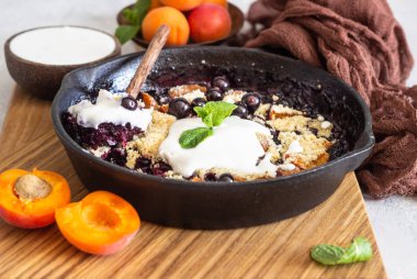 Dökme demir Pan içinde crumble ve kayısı ile Doğal yoğurt ve min. sağlıklı gıda konsepti ile servis. 