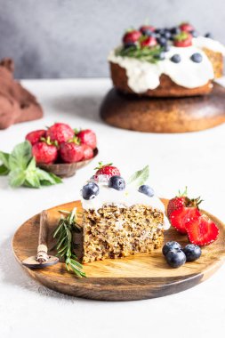 Kabaklı, havuçlu ve cevizli tam tahıllı kek çırpılmış krema, çilek, yabanmersini, nane ve biberiye ile süslenmiş ahşap tabakta.. 