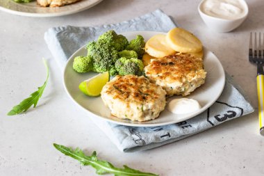 Lezzetli pirzola (balık veya et) brokoli, patates ve sos ile bir tabakta. Açık gri taş arka plan. 