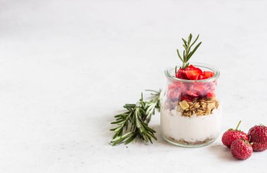 Hafif taş arka plan üzerinde bir mason kavanozda yoğurt, granola ve taze çilek ile Kahvaltı. Sağlıklı kahvaltı veya tatlı konsepti, seçici odak. Kopyalama alanı.