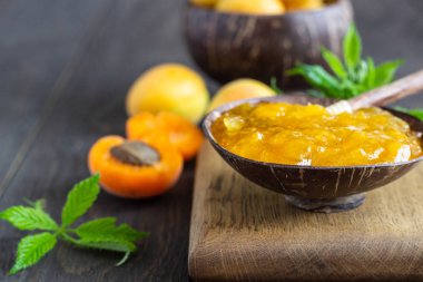 Ahşap bir kapta kayısı reçeli ve ahşap bir arka plan üzerinde taze kayısı. Kopya alanı. Yaz hasat konsepti.