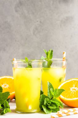 Açık gri taş masa üzerinde taze portakal ve nane ile cam portakal limonata. Serinletici yaz içkisi. Kokteyl bar arka plan konsepti. Kopyalama alanı.