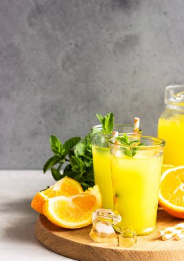 Açık gri taş masa üzerinde taze portakal ve nane ile cam portakal limonata. Serinletici yaz içkisi. Kokteyl bar arka plan konsepti. Kopyalama alanı.