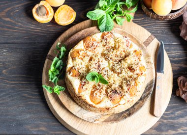 Kayısı ve ufalanmış cheesecake, taze kayısı ve nane. Ahşap arka plan, rustik tarzı. Kopyalama alanı.